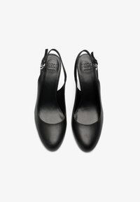 Μαύρες δερμάτινες slingback πατούσες με λεία υφή, στρογγυλή μύτη και ρυθμιζόμενο λουράκι με ασημένια λεπτομέρεια αγκράφας.