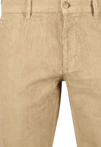 Beige ribfluwelen broek met verticale ribbels, riemlussen, een knoopsluiting en een gulp aan de voorkant.