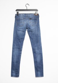 Jeans ajustados de mezclilla azul con una textura suave, cintura media, dos bolsillos traseros y un lazo para colgar.