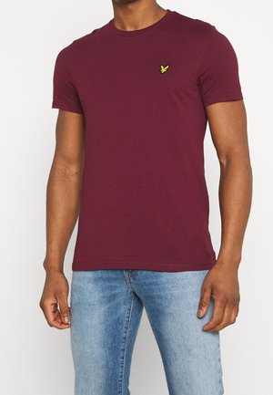 T-shirt bordeaux en coton avec un col rond. Présente un petit logo vert brodé sur la poitrine. Design ajusté.