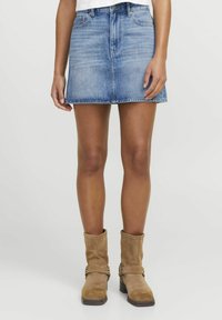 Lys blå denim miniskjørt med klassisk fem-lommersdesign og rå kant. Kombinert med lysebrune suede ankelstøvler.