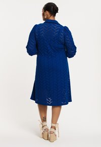 Koninklijk blauwe jurk met een gestructureerd patroon, pofmouwen en een kraag. Gecombineerd met tan espadrille wedges met lintaccenten.