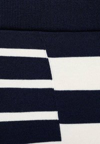 Marineblauw en witte gestreepte stof met afwisselende horizontale banen. Getextureerde brei met ribbels aan de bovenkant, wat een gestructureerd uiterlijk creëert.