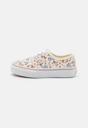 Lave canvas-sneakers med hvid sål, snørebånd og et flerfarvet rødt, blåt og sort blomsterpatron på beige baggrund.