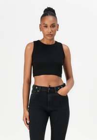 Black ribbed crop top with a round neckline and sleeveless design, paired with high-waisted black jeans featuring a five-pocket style.