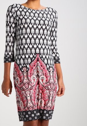 Vestido de patrón blanco y negro con mangas tres cuartos, que presenta un diseño ornamentado en rojo y rosa en la mitad inferior y un borde de acento negro.