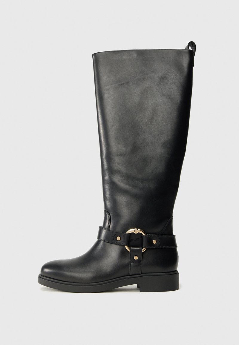 Ψηλό μαύρο δερμάτινο μποτάκι με χαμηλό τακούνι και διακοσμητικό χρυσό δαχτυλίδι και ζώνη γύρω από τον αστράγαλο.