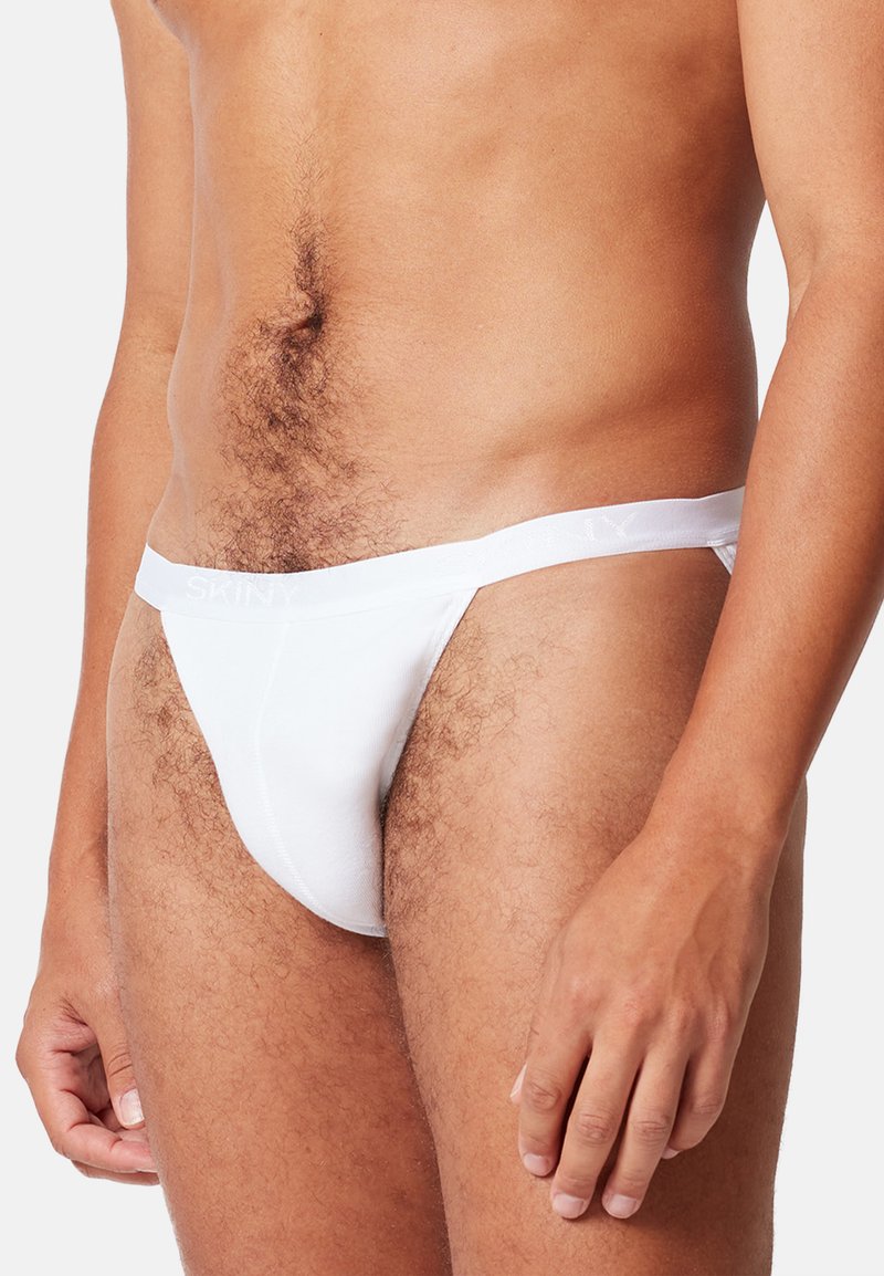 Witte katoenen string met een zachte tailleband met merkopdruk. Gladde textuur, vormgevende fit, minimale bedekking en elastische zijkanten.