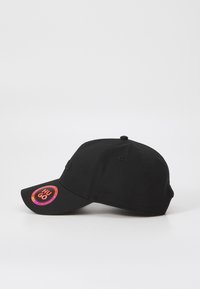 Svart baseballcap laget av bomull med buet skjerm, med et sirkulært rødt og oransje logopatch på fronten. Enkelt og tettsittende design.