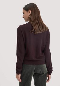 Burgundy neule, jossa on pitkät hihat, röyhelötyynyt ja helma. Pehmeä rakenne, suora malli. Puettua oliivinvihreiden samettihousujen päälle.