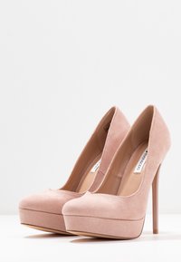 Růžové lodičky na vysokém podpatku s semišovou texturou, kulatou špičkou, předním platformou a tenkým stiletto podpatkem. Viditelné hladké vnitřní podložení.