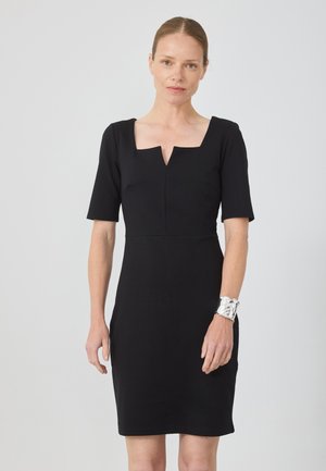 Black fitted dress featuring a square neckline, short sleeves, and a smooth, textured fabric. Silver metallic cuff bracelet on the wrist.