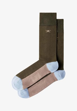 Paire de chaussettes mi-mollet avec partie supérieure vert olive, section pied marron, talon et orteils bleu clair, et petit logo de clubs de golf croisés près du bord-côte.
