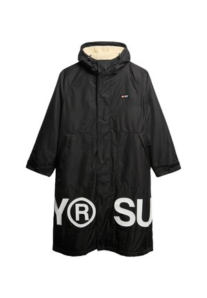 Cappotto lungo nero con cappuccio, con testo bianco sul davanti, foderato con un tessuto texturizzato e dotato di due tasche frontali. Realizzato in un materiale resistente all'acqua.