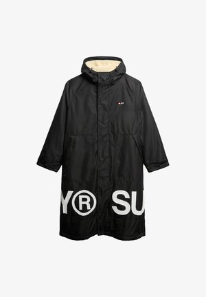 Cappotto lungo nero con cappuccio, con testo bianco sul davanti, foderato con un tessuto texturizzato e dotato di due tasche frontali. Realizzato in un materiale resistente all'acqua.