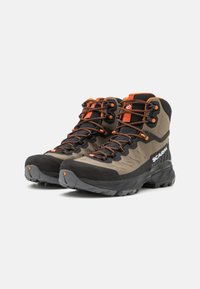 Hiking boots in dark gray and khaki with orange accents, featuring a high-top design, textured upper, and rugged sole for traction.