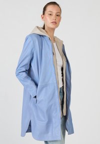 Vaaleansininen nahkatakki, jossa on beige huppu, vetoketjukiinnitys ja sivutaskut. Ominaisuuksiin kuuluu sileä pinta ja rento malli.