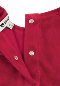 Rotes Baumwollkleidungsstück mit Druckknöpfen am Halsausschnitt, weicher Textur und einem Etikett mit Bärenlogo. Größe 62, geeignet für 2-3 Monate.