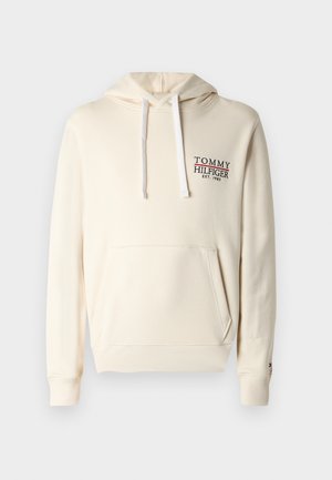 Kremowa bluza z kapturem z kieszenią z przodu, sznurkami i wyszywanym logo "TOMMY HILFIGER" w czerni i czerwieni. Miękki, teksturowany materiał.