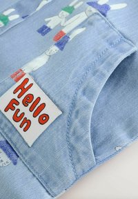 Jeans oblačilo svetlo modre barve z igrivimi ilustracijami zajčkov, na robu shemirano z etiketo "Hello Fun" v rdeči in beli barvi.
