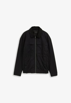 Zwarte jas met ritssluiting, lange mouwen, twee borstzakken, elastische tailleband en een zachte, getextureerde kraag.