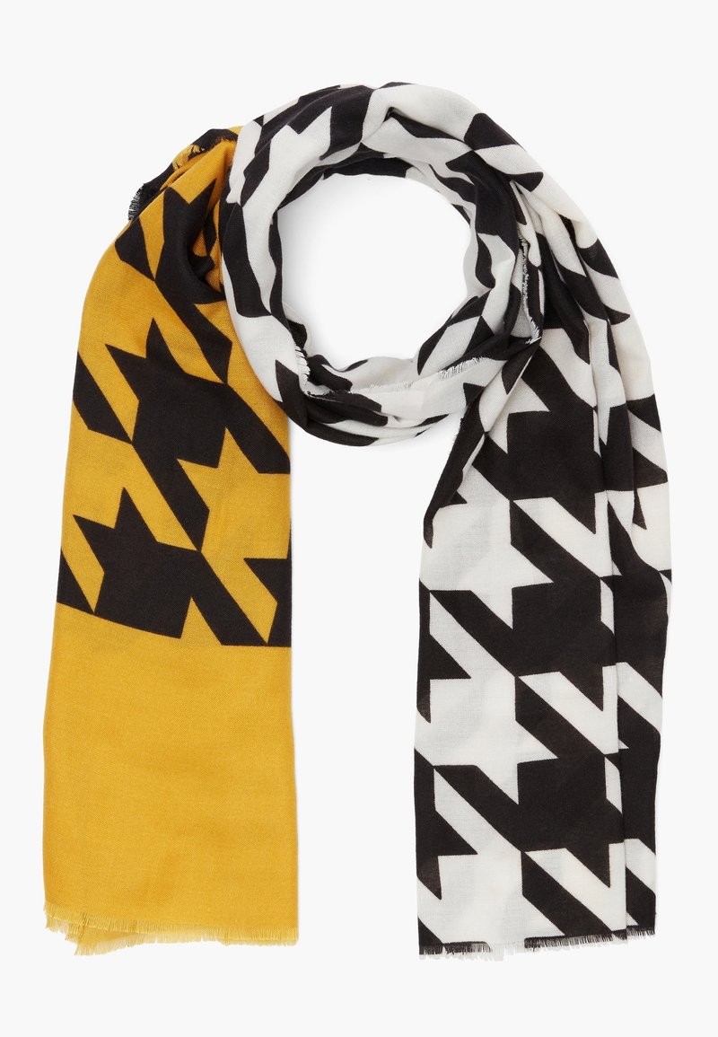 Écharpe à motif pied-de-poule large, un côté jaune moutarde avec des formes noires, l'autre côté blanc avec des formes noires, pliée de manière lâche.