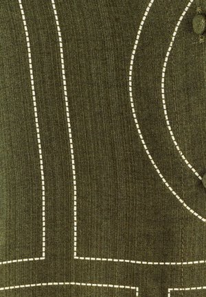 Olivgrüner Stoff mit kontrastierenden weißen Nähten. Enthält gewellte und gerade Linien, die ein strukturiertes Muster erzeugen. Beinhaltet ein Knopfdetail.