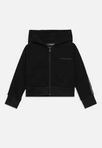 Hoodie cropped preto feito de tecido macio. Apresenta um fecho frontal, capuz e bainha canelada. A manga esquerda tem detalhes decorativos.