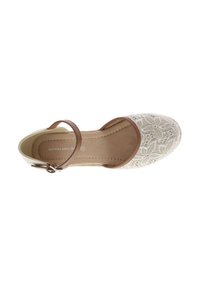 Chaussure beige avec un dessus texturé et brodé ainsi qu'une sangle marron à la cheville. L'intérieur est doublé d'un matériau doux. Conception à bout rond.