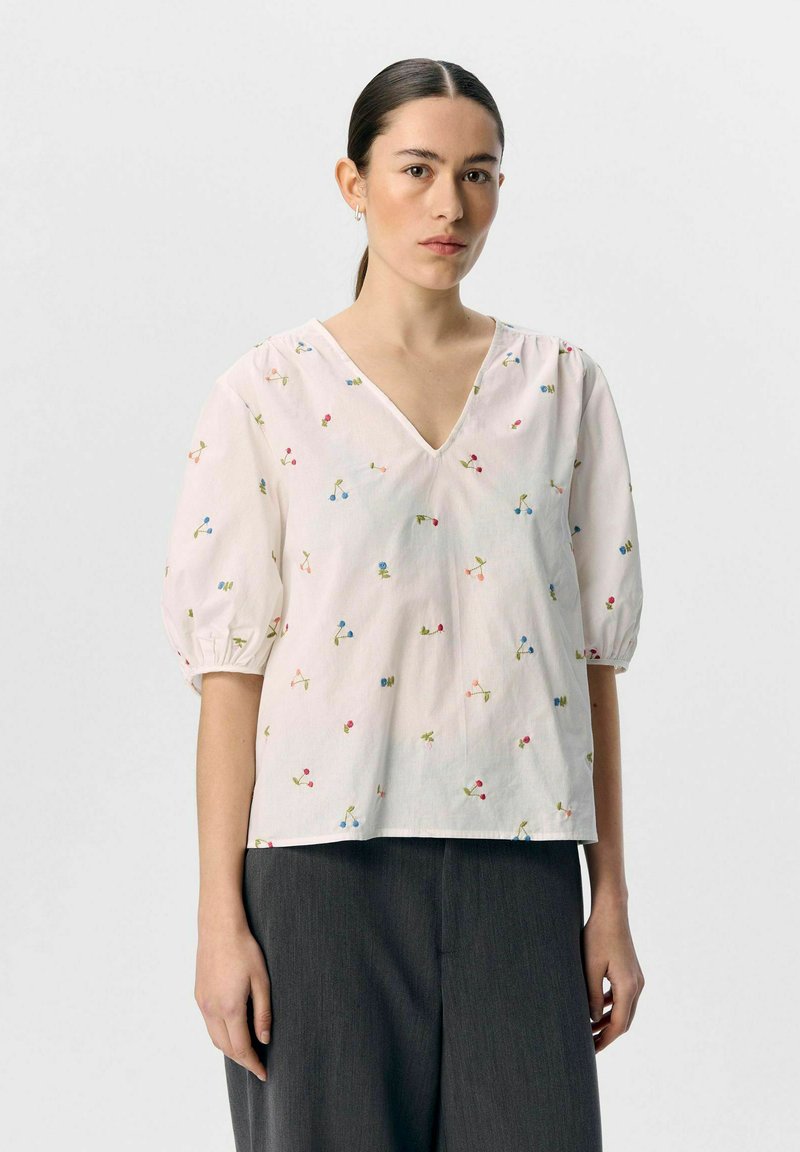 Witte, korte mouwen blouse met een V-hals, met kleurrijke bloemembroidery en een relaxte pasvorm. G gedragen met grijze, wijde broek.