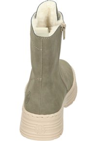 Bottines en suede vert avec doublure en fausse fourrure blanche, fermeture éclair arrière et semelle en caoutchouc beige avec des rainures horizontales et un détail de logo.