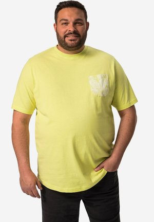 Gelbes Baumwoll-T-Shirt mit Rundhalsausschnitt und kurzen Ärmeln, ausgestattet mit einer gemusterten Tasche. Die Passform ist locker und ergänzt dunkel Hosen.