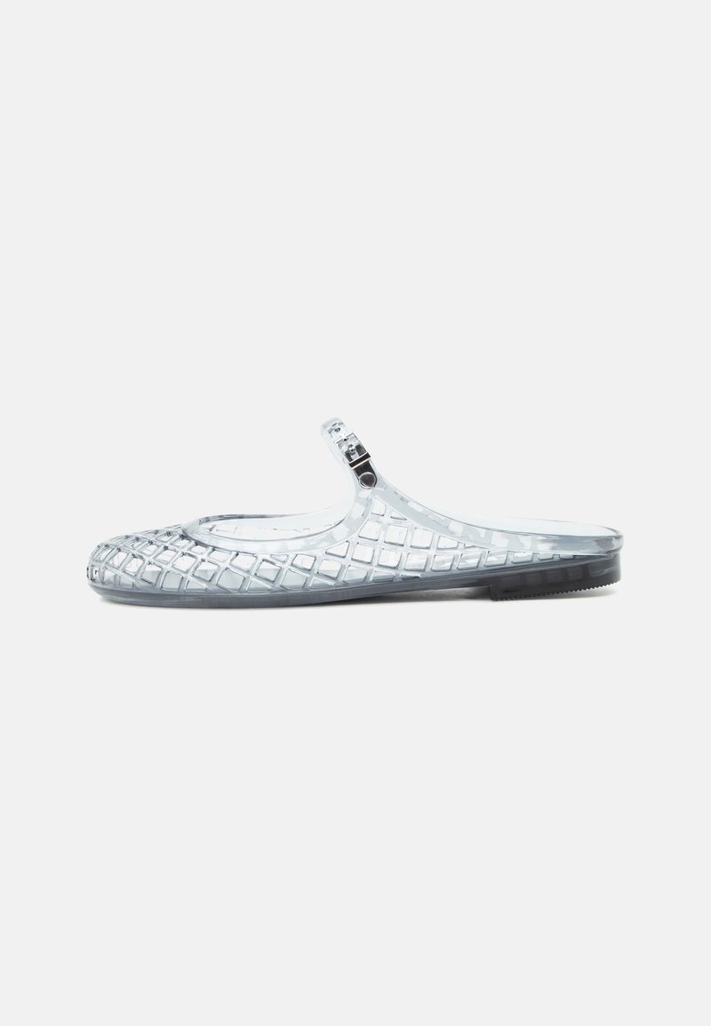 Chaussure plate transparente à enfiler avec une texture à motif diamant et une petite bride réglable sur la partie supérieure.