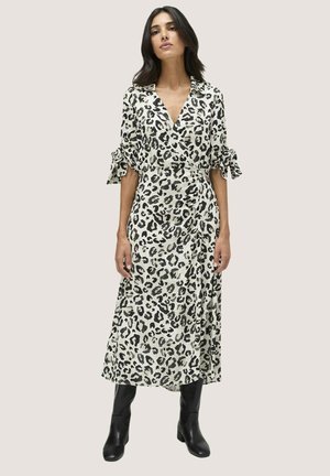 Vestido de leopardo en beige y negro. Presenta un escote en V, mangas cortas con lazos y longitud midi. El material parece suave y ligero.