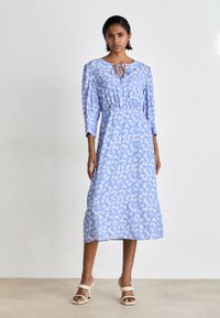 Rochie bleu deschis cu un model abstract alb subtil, mâneci trei sferturi, talie strânsă și decolteu rotund cu un detaliu de sfoară.