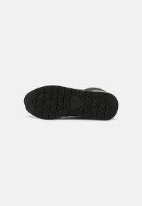 Sole di scarpa in gomma nera con un motivo testurizzato che presenta forme esagonali. Design piatto con una costruzione solida e durevole.