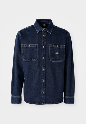 Dark blue denim shirt with a collar, front button closure, two chest pockets, golden buttons, and visible stitching. Features a brand logo.