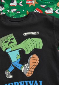 Svarta bomullströjor med Minecraft-motiv. En tröja visar en grön karaktär som springer; den andra har ett färgglatt TNT-mönster.