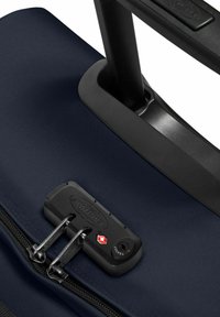 Námořnický cestovní kufr s texturovaným vnějším povrchem, dvojitými zipy, zámkem schváleným TSA a zatahovací černou rukojetí.