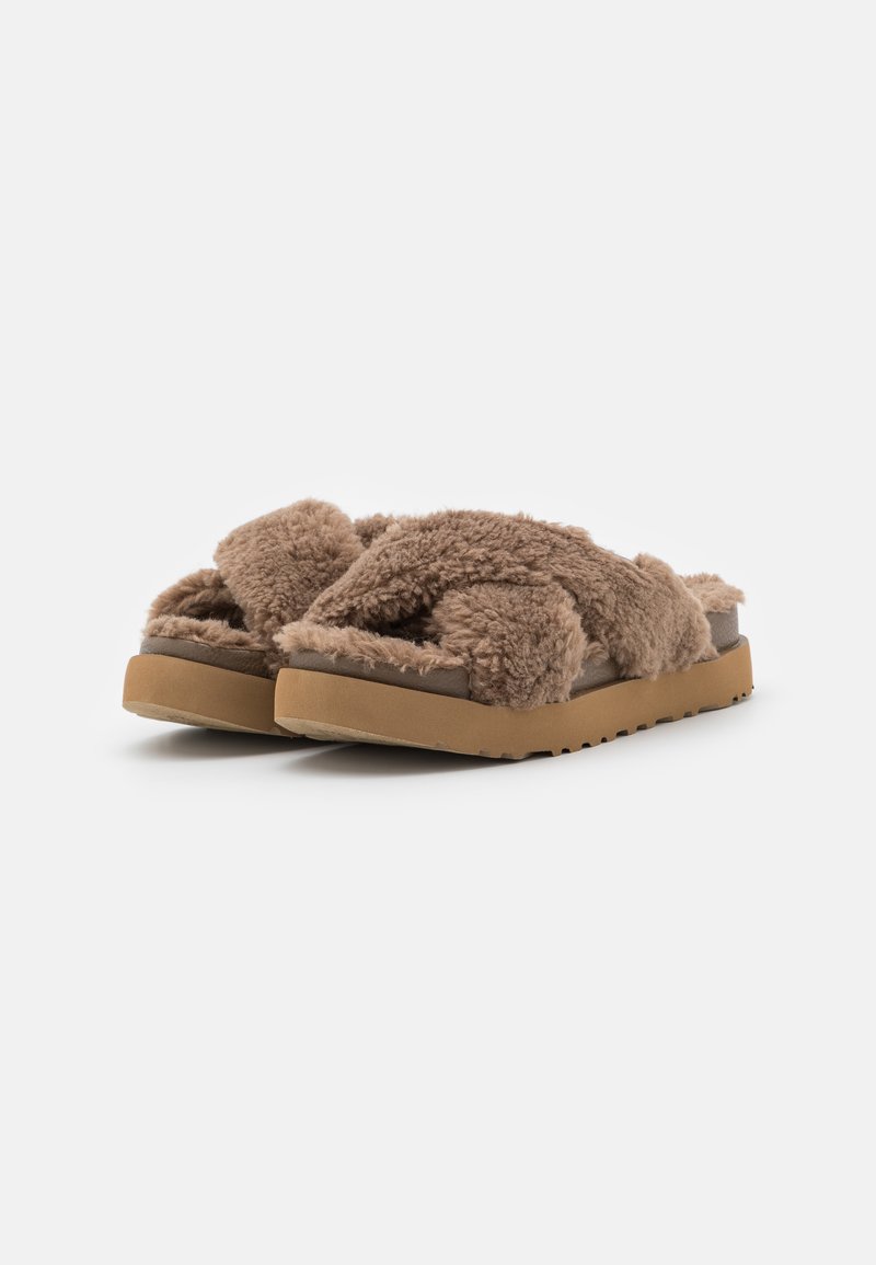 Chanclas de shearling marrones con un upper texturizado y suave y una suela de goma. Presentan un diseño de banda cruzada para mayor comodidad y un estilo de fácil puesta.