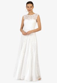 Robe en dentelle blanche avec un corsage ajusté et une jupe évasée. Présente un col en dentelle transparente, des manches courtes et des détails de motifs floraux.