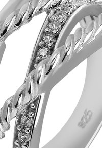 Bague en argent avec un design torsadé, accentuée de petites pierres claires. Marquée "925" pour l'argent sterling à l'intérieur de l'anneau.