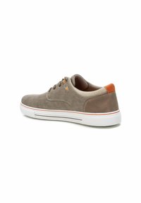 Zapatilla de lona gris con suela de goma blanca, acentos de ante marrón y costuras naranjas. Presenta cordones redondos y detalles perforados en el talón.