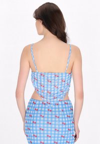 Blå gingham-kjole med kirsebærprint, spaghettistropper og udskæringer ved taljen, med en tætsiddende silhuet.