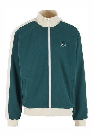 Sinivihreä vetoketjullinen takki valkoisilla yksityiskohdilla, jossa on korkea kaulus, kaksi sivutaskua ja pieni logo rinnassa. Pehmeä kangaspinta.