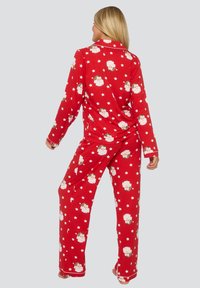 Roter Pyjama-Set aus weichem Stoff, mit festlichen Weihnachtsmann- und Sternmustern. Lange Ärmel und Hose mit elastischem Bund.
