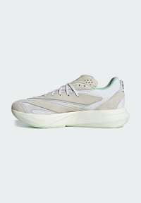 Jasnoszare buty sportowe z siateczki i zamszu. Charakteryzują się białymi akcentami, zaokrąglonym noskiem i grubą, zielonkawą podeszwą.