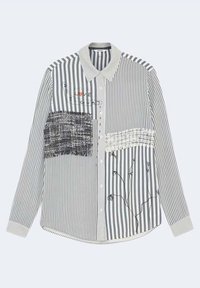 Camicia abbottonata con strisce verticali bianche e nere, con toppe in tessuto testurizzato e accenti di ricamo floreale. Design con colletto e maniche lunghe.