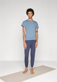 Light blue short-sleeve top with a round neckline, paired with navy tapered pants featuring elastic cuffs and side pockets.