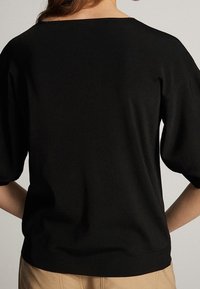 Zwarte gebreide trui met een brede halslijn, korte pofmouwen en geribde zoom. Zachte textuur en eenvoudig design.